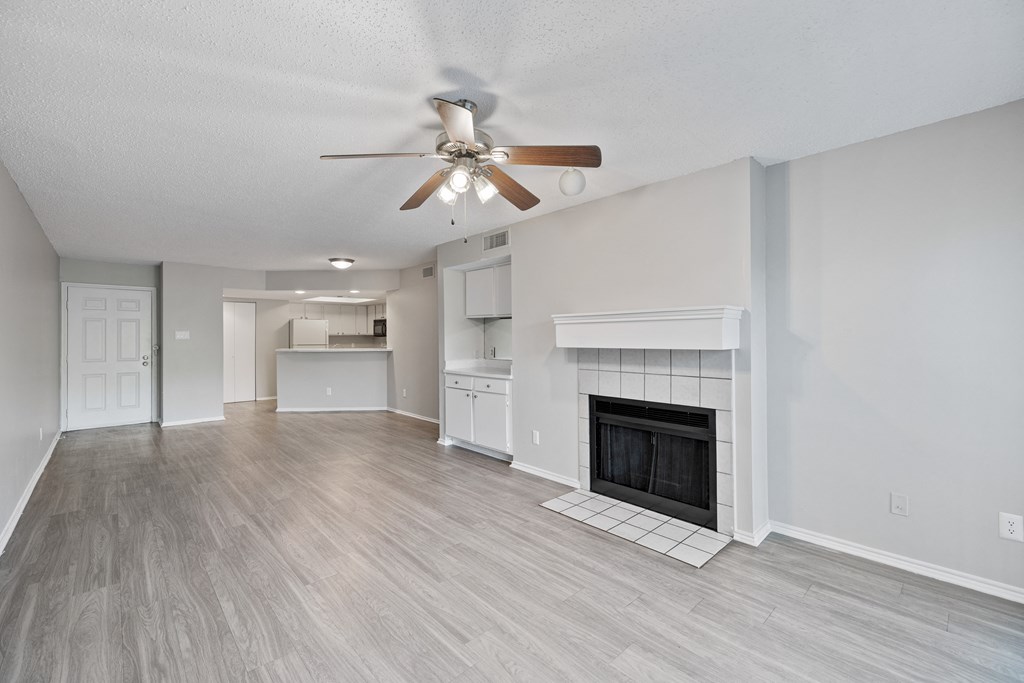 A spacious living room with a fireplace and a ceiling fan.