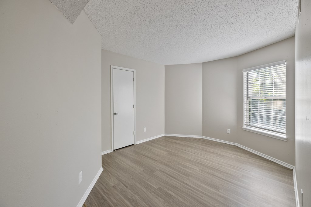 A room with a door, window, and wooden flooring.