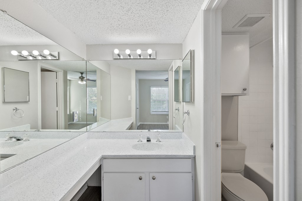 A white bathroom with a vanity and a toilet.