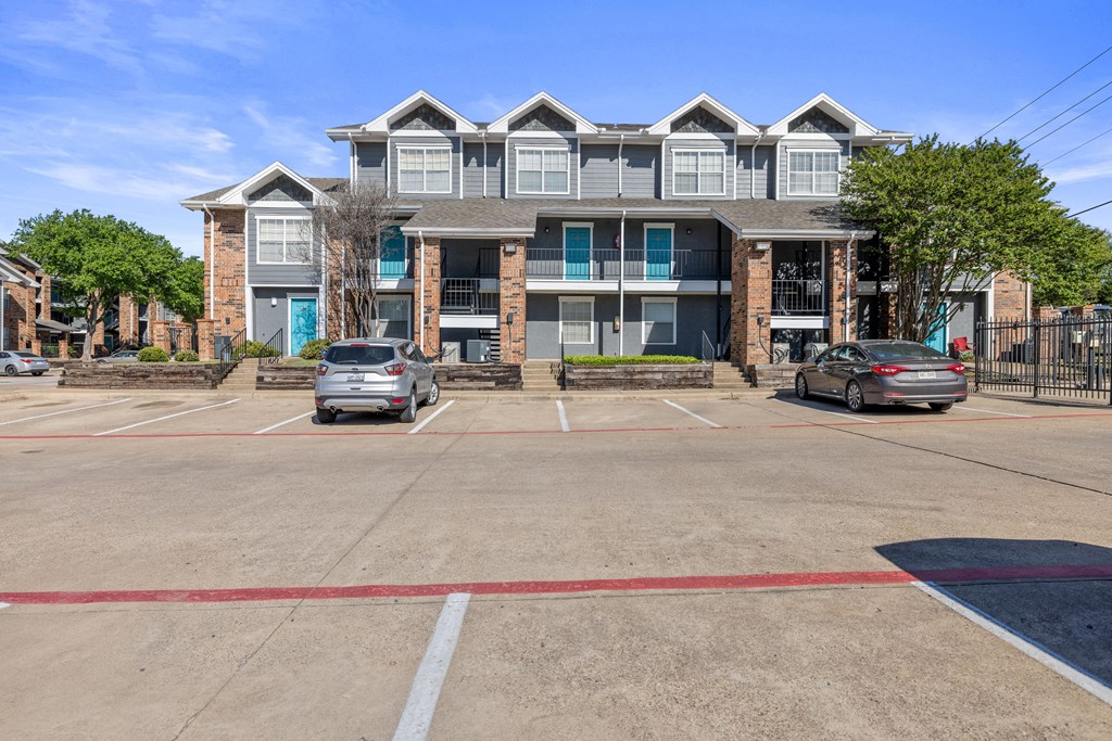 A parking lot in front of a multi-story apartment building.