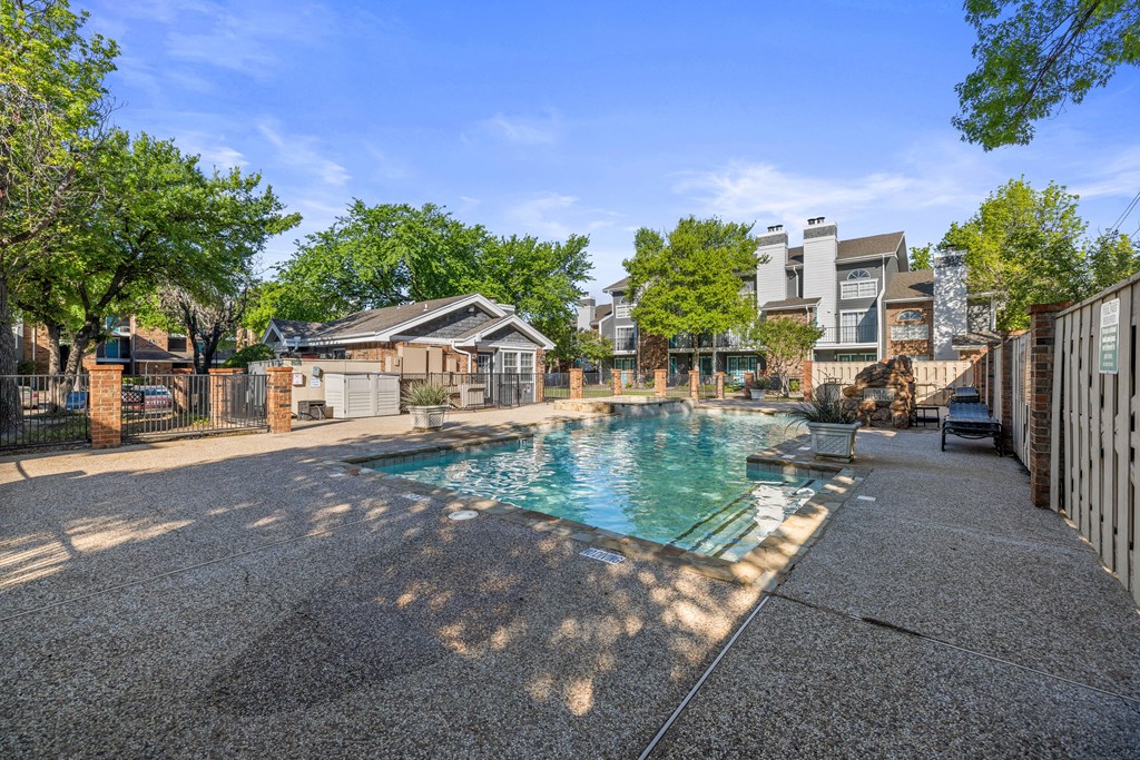 A residential area with a pool surrounded by houses and trees.