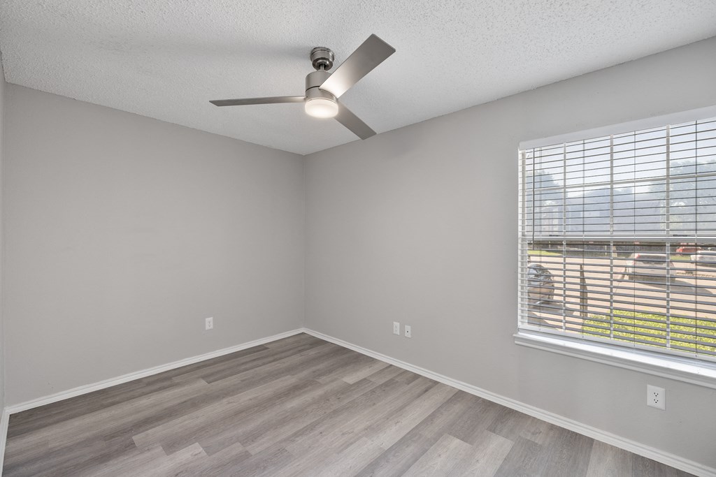 A room with a ceiling fan and a window with blinds.