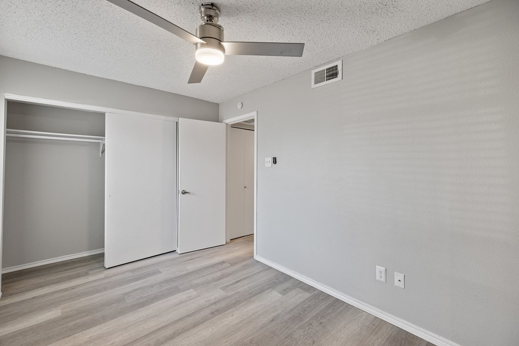 A room with a ceiling fan and a white door.