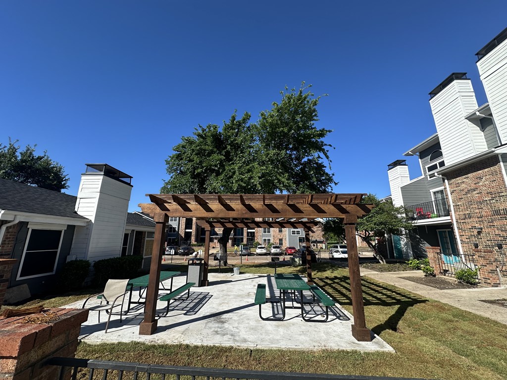 A patio with a table and chairs under a pergola.