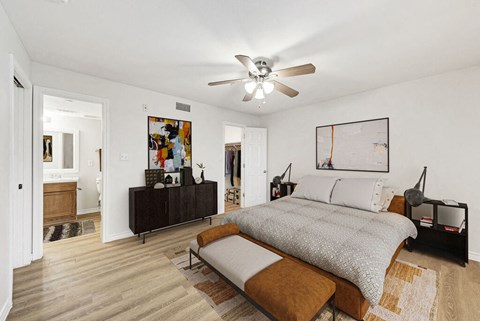 A bedroom with a bed, a bench, and a ceiling fan.