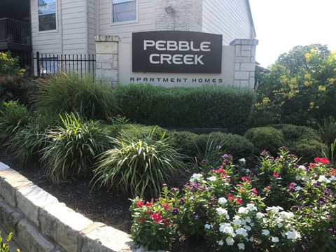 A sign for Pebble Creek Apartment Homes is in front of a building.