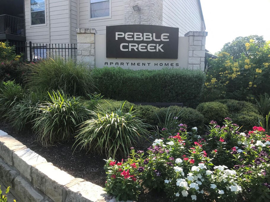 A sign for Pebble Creek Apartment Homes is in front of a building.