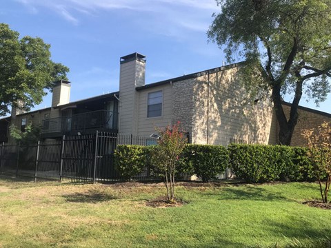 A house with a black fence and a tree in front.