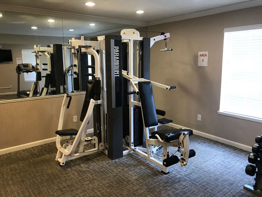 A gym with a mirror, weights, and a Parade brand machine.