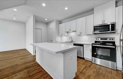 A modern kitchen with stainless steel appliances and wooden floors.