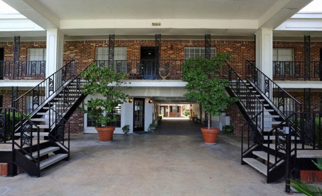 A courtyard with a black railing and a brick building.