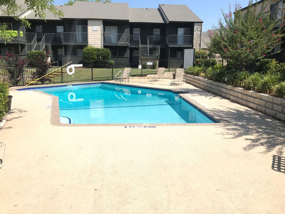 A small pool in a backyard with a building in the background.
