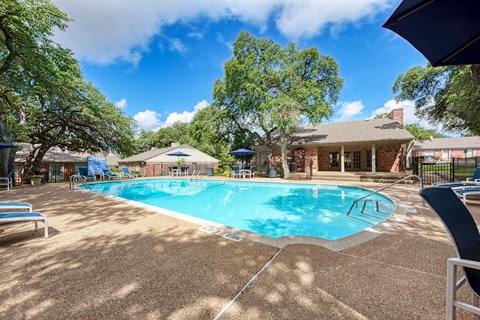 A pool surrounded by trees and a house.