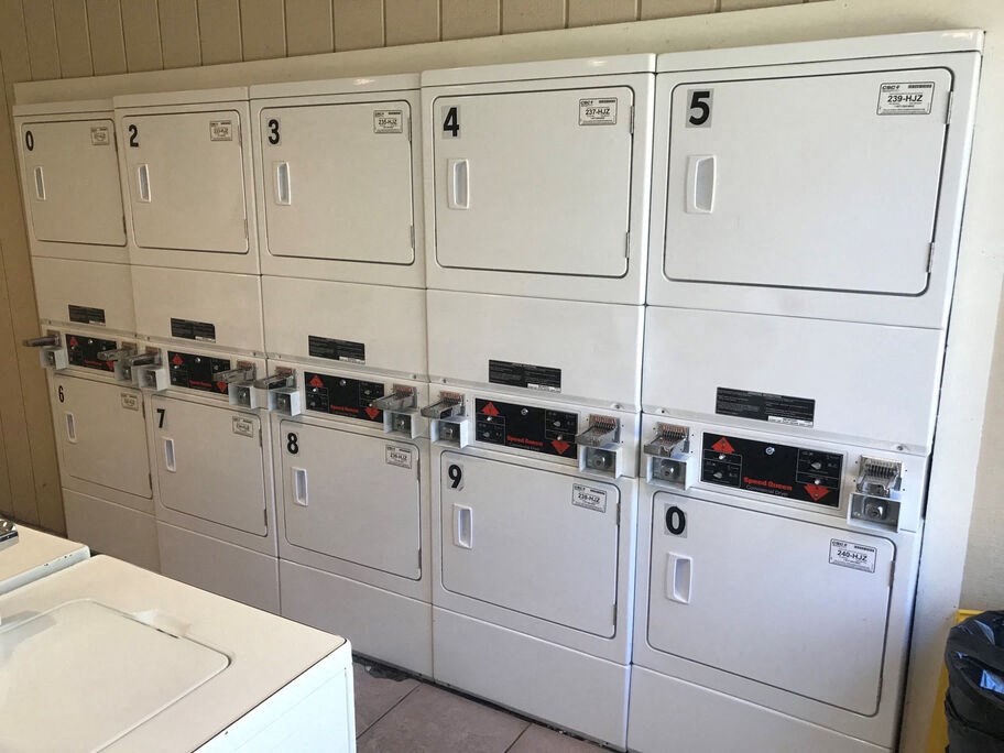 A row of white washing machines with numbered doors.