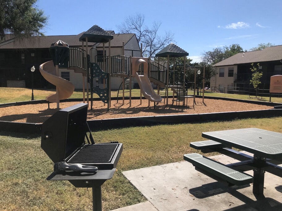 A playground with a slide, swings, and picnic tables.