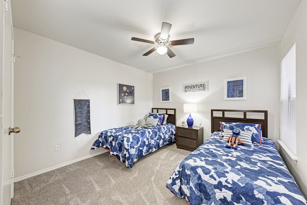 A bedroom with two beds and a ceiling fan.