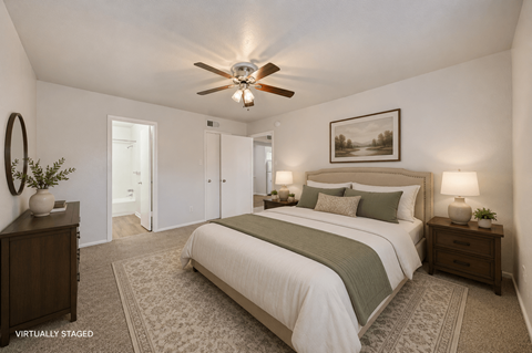 A bedroom with a bed, nightstands, and a ceiling fan.
