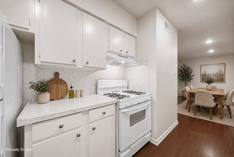 A white kitchen with a stove and a dining table.