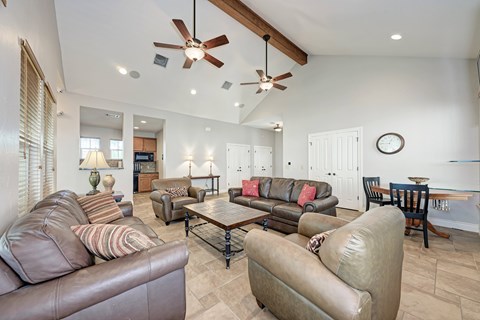 A living room with brown leather couches and a ceiling fan.
