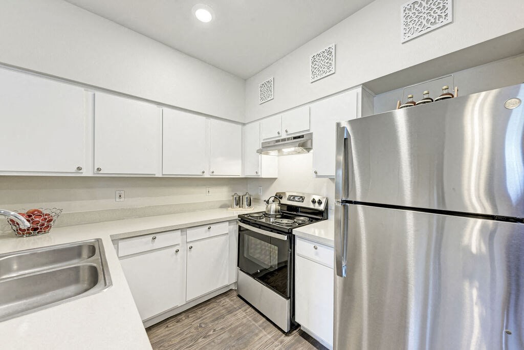 A modern kitchen with white cabinets and stainless steel appliances.