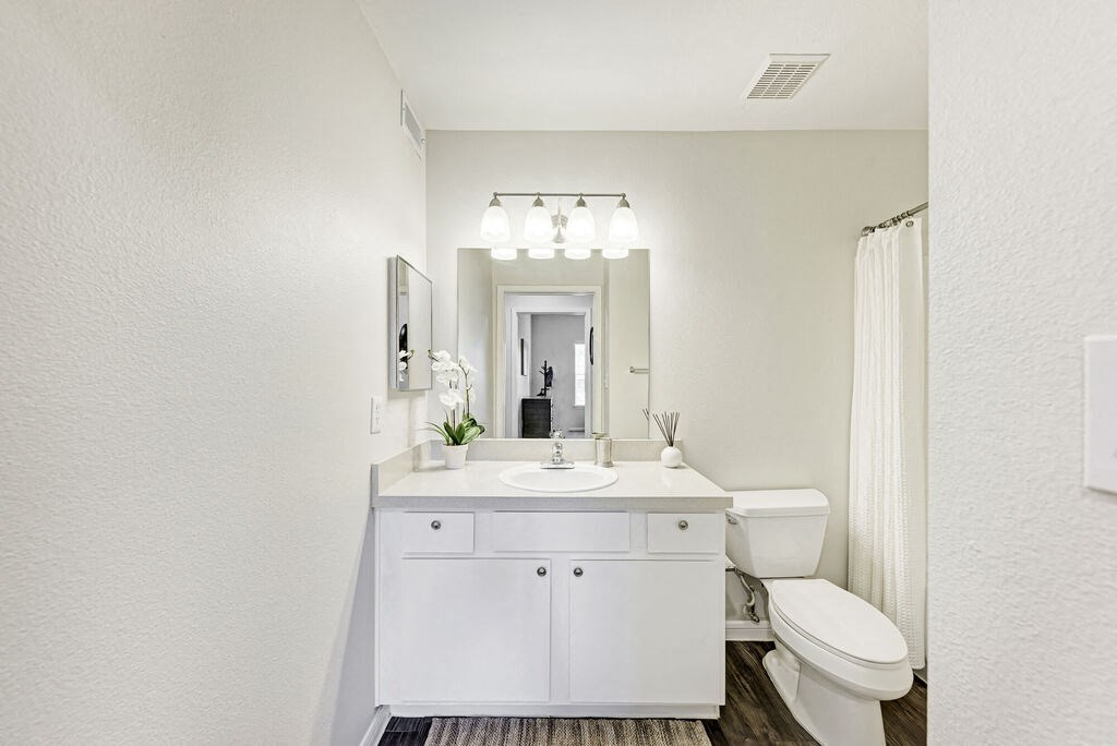 A white bathroom with a sink, toilet, and mirror.
