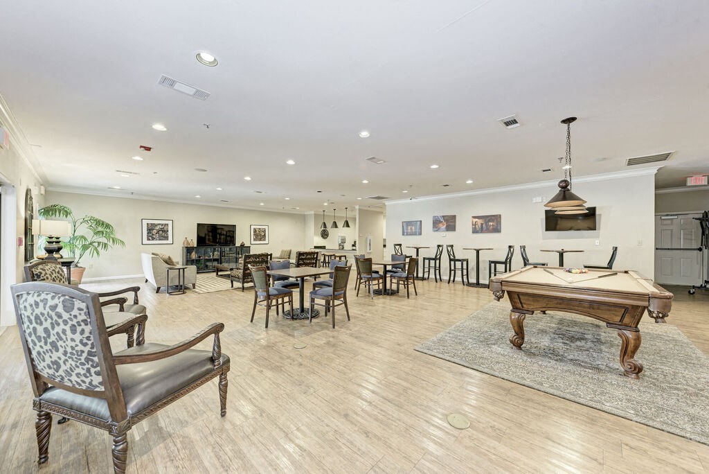 A room with a pool table and chairs.