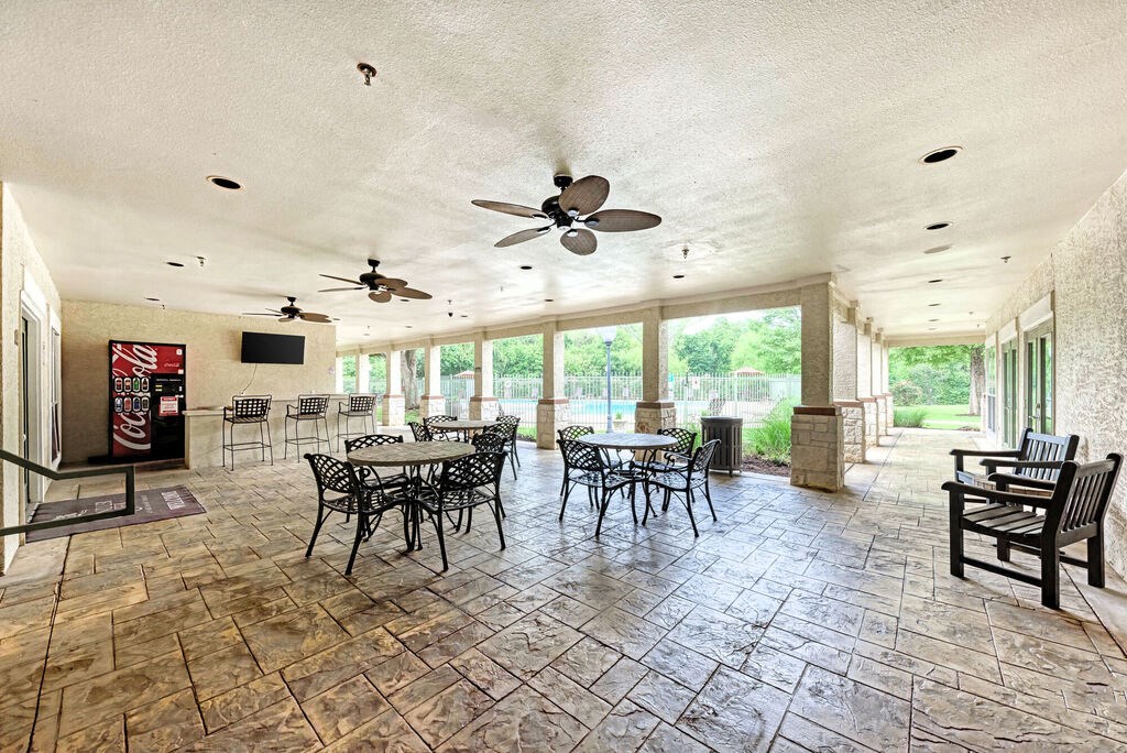 A patio with a table and chairs and a ceiling fan.
