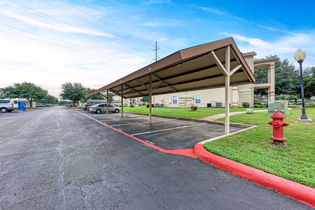 A parking lot with a red fire hydrant and a building in the background.