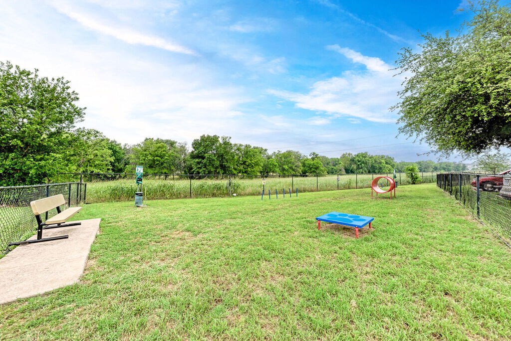 A park with a blue bench and a red object in the middle of the grass.