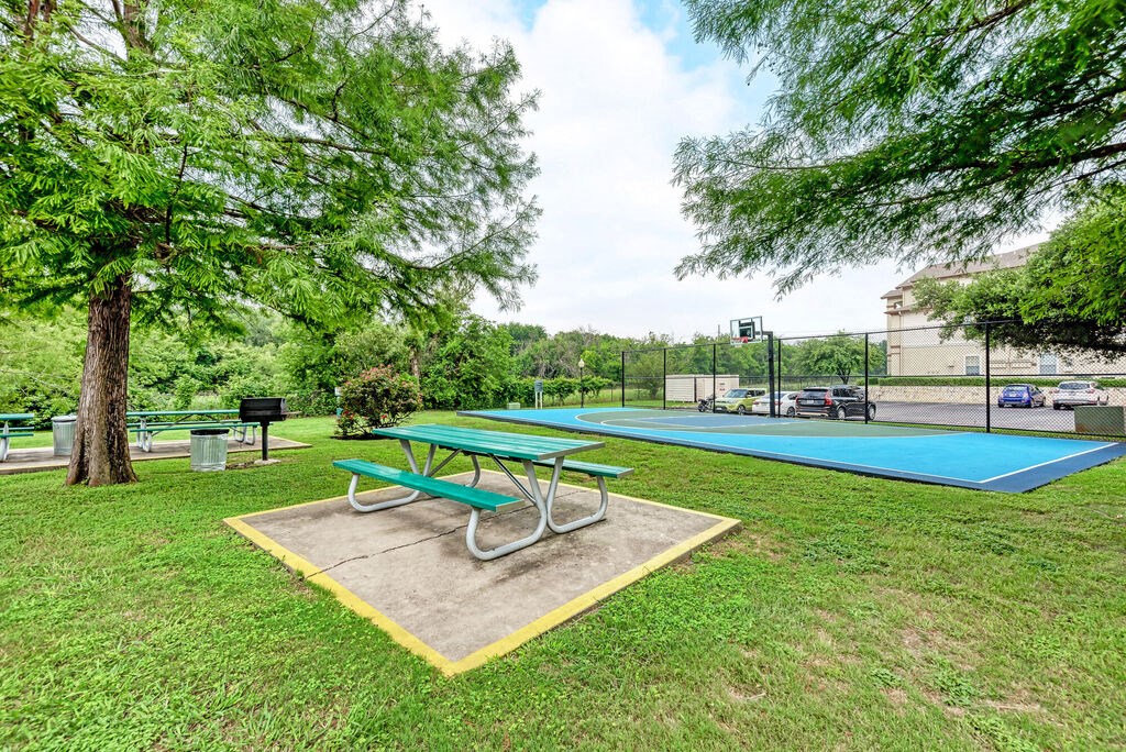 A green picnic table is in the middle of a grassy area.