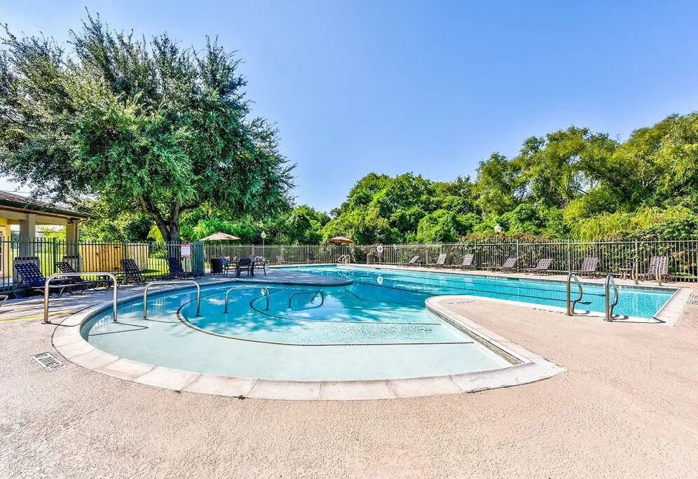 A round swimming pool surrounded by a fence and trees.