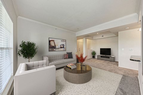 A living room with a white couch, a coffee table, and a television.