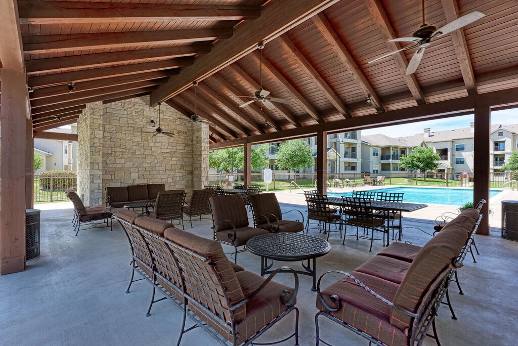 A patio with a table and chairs and a pool in the background.