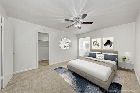 A bedroom with a bed, a ceiling fan, and pictures on the wall.