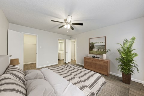 A bedroom with a bed, dresser, and ceiling fan.