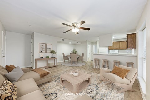 A living room with a beige couch, a coffee table, and a ceiling fan.