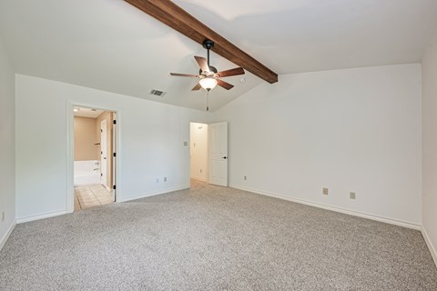A spacious room with a ceiling fan and carpeted floor.
