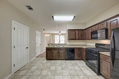 A kitchen with brown cabinets and black appliances.