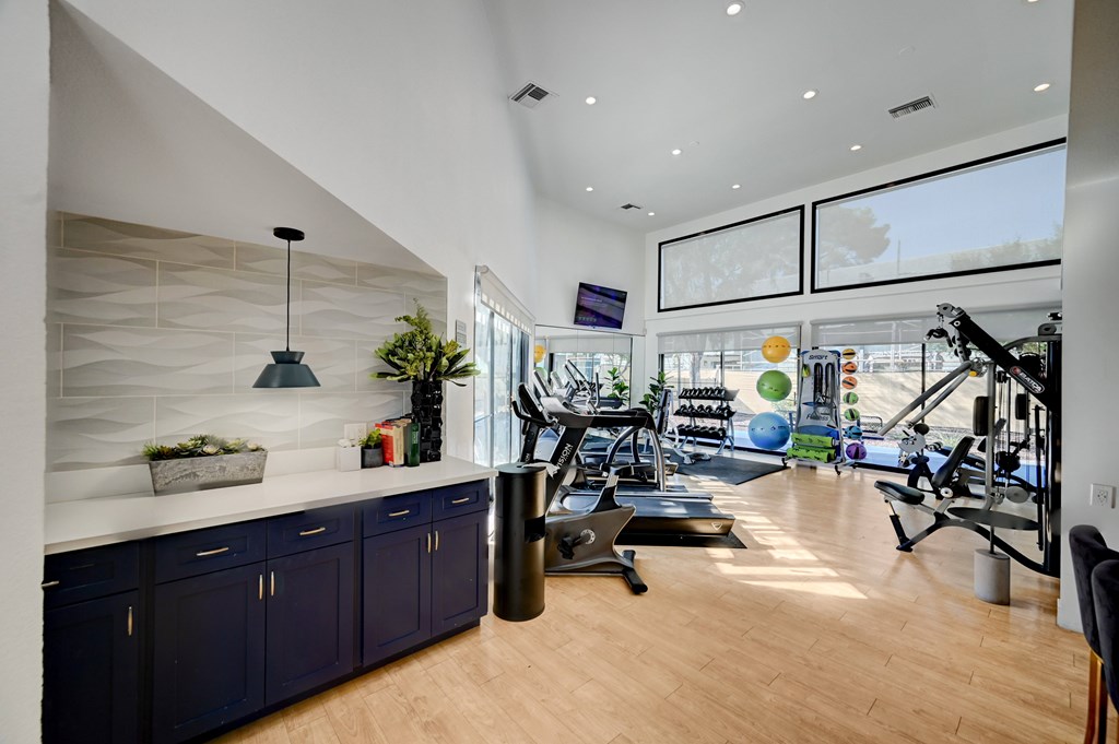 A spacious home gym with a variety of exercise equipment and a large mirror on the wall.