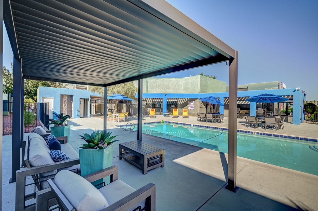 A pool area with a canopy and lounge chairs.