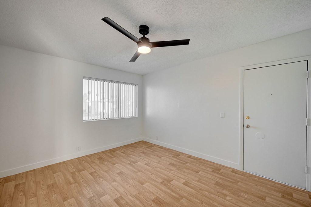 A room with a ceiling fan and wooden flooring.