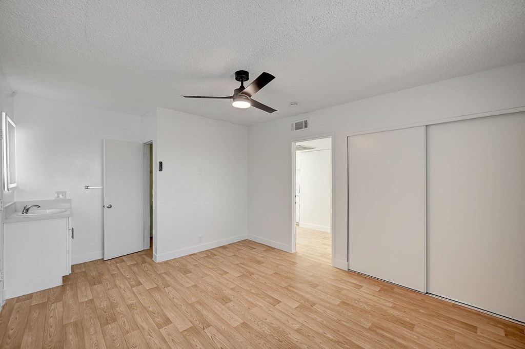 A room with a ceiling fan and wooden flooring.