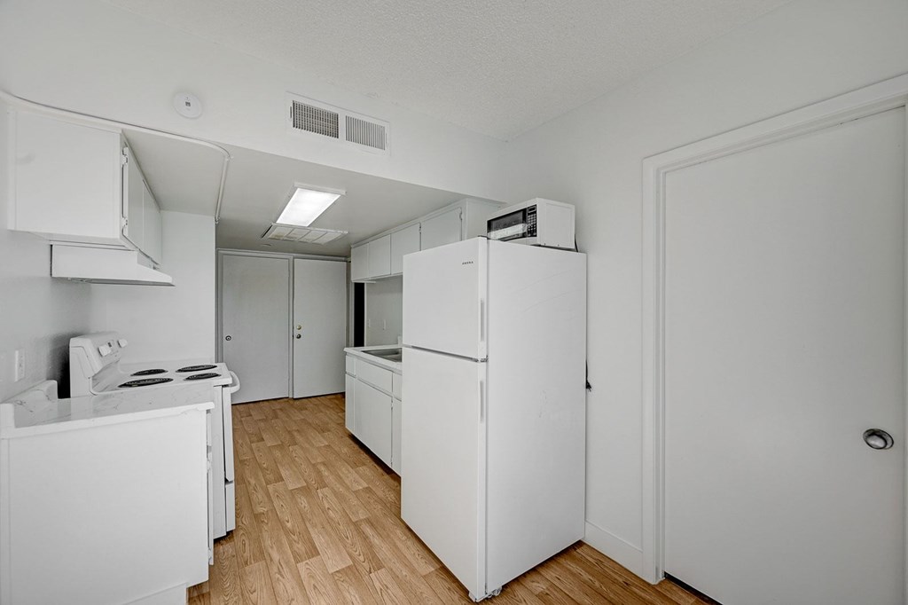A white kitchen with a stove, refrigerator, and oven.