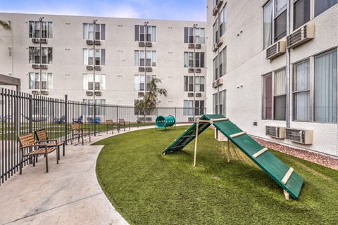 A playground with a green slide in front of a building.