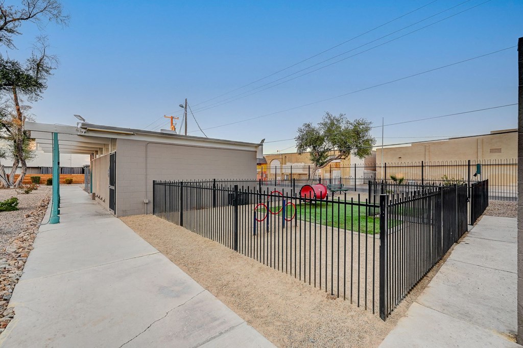 A black fence surrounds a building with a green post in front.