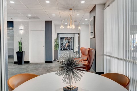 A modern conference room with a white table and orange chairs.