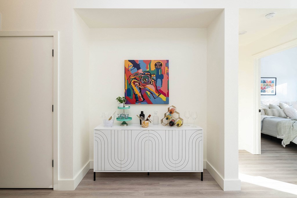 A painting hangs on the wall above a white bench with a striped pattern.