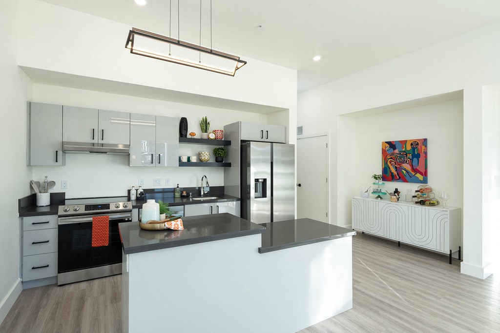 A modern kitchen with a black countertop and stainless steel appliances.