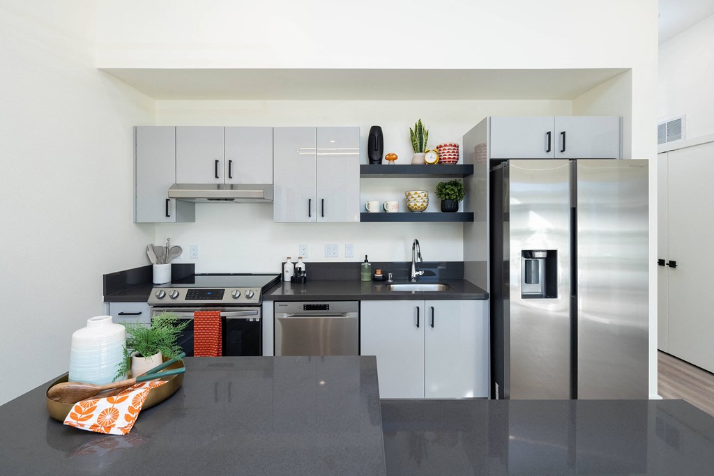 A modern kitchen with a black countertop and stainless steel appliances.
