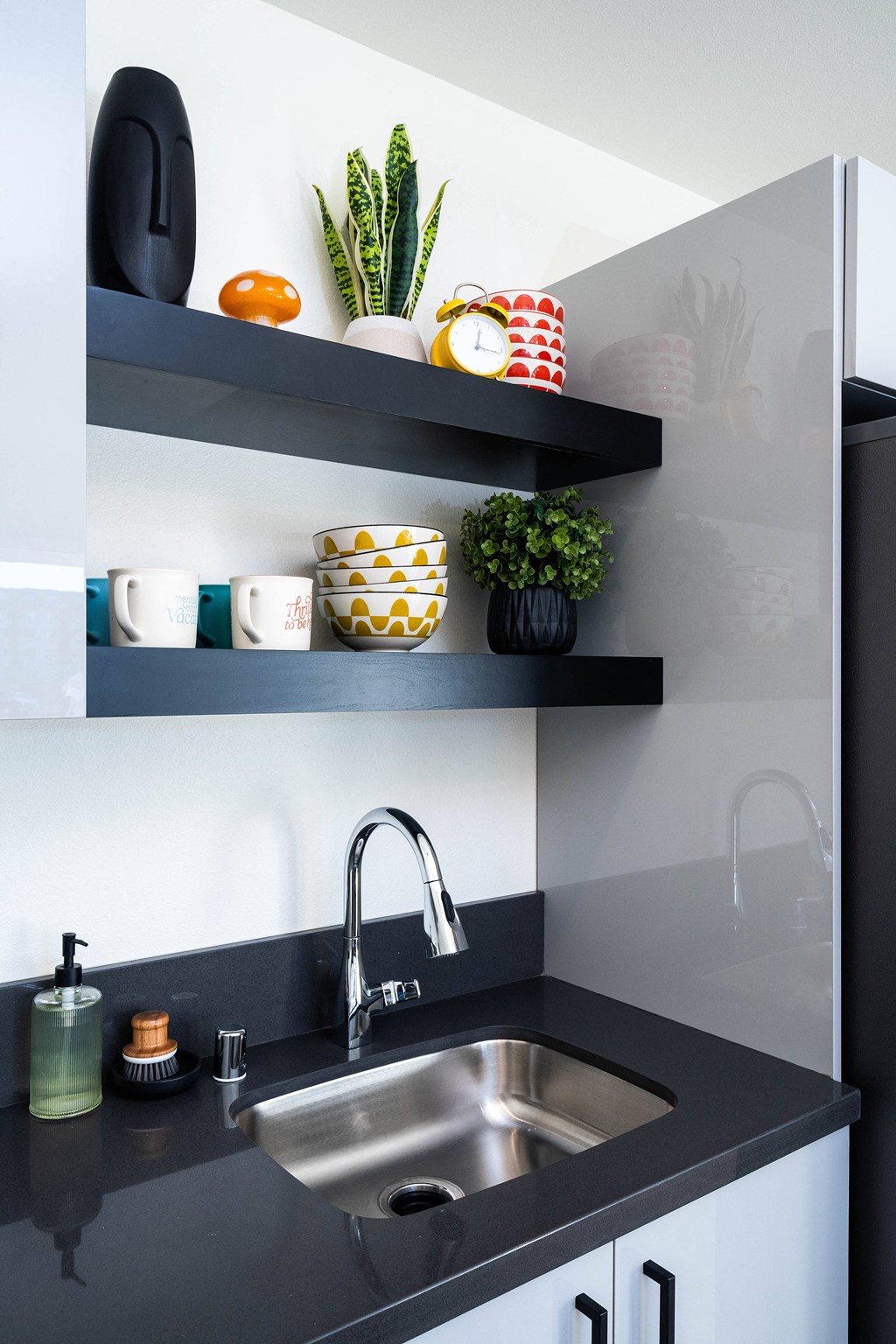 A kitchen with a black countertop and a stainless steel sink.